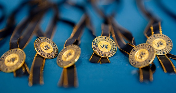 Close up of gold Health and Human Rights pin that features the Drexel Dragon